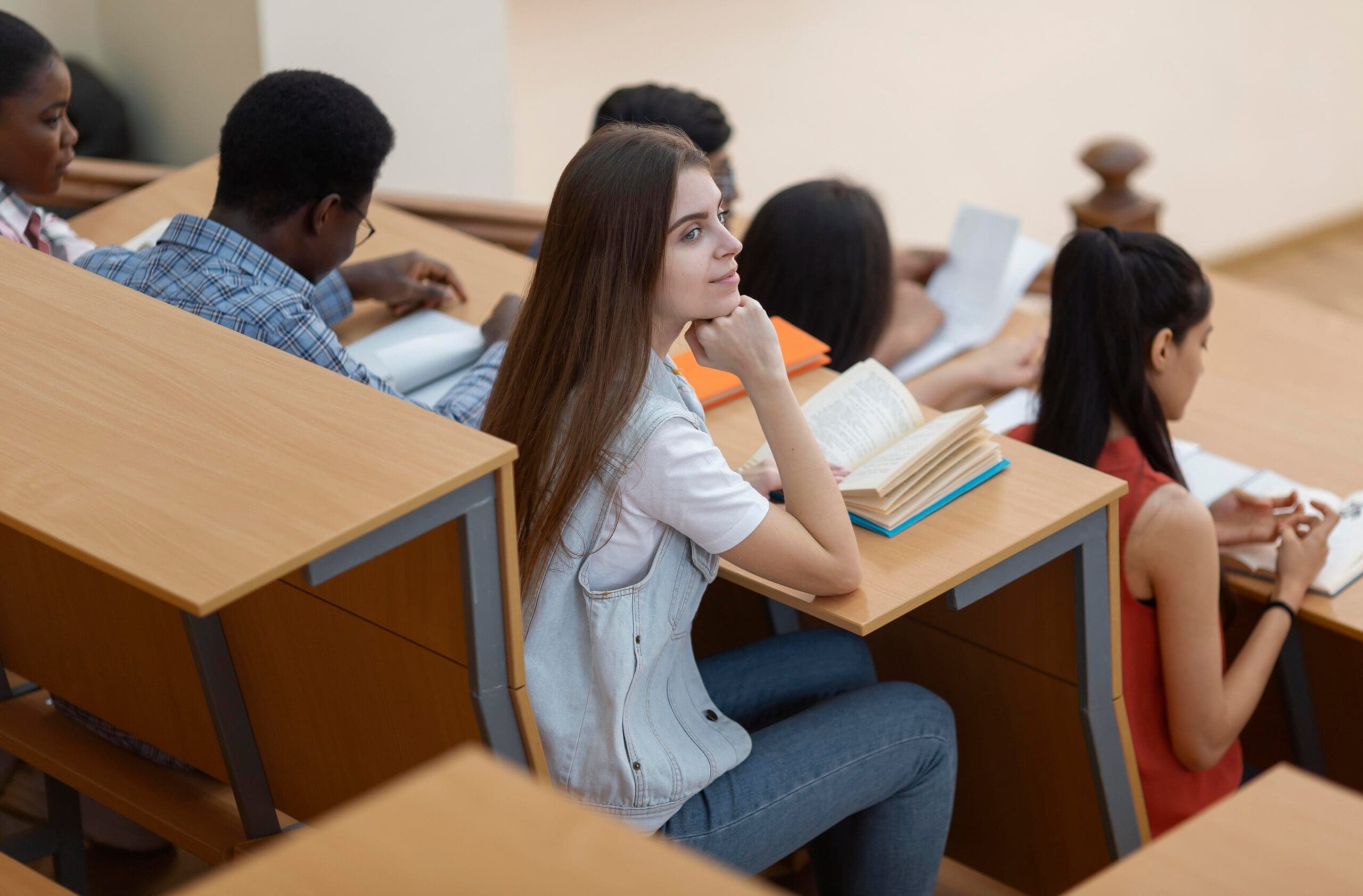 Students studying and reading books at desks in a classroom